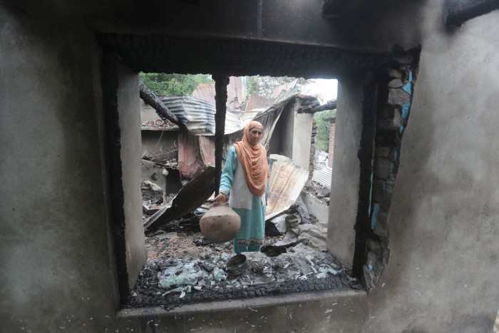 Una mujer de Cachemira lleva un utensilio rescatado de su casa dañada después de un bombardeo transfronterizo de Pakistán