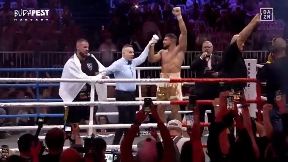 Boxer levanta las manos en la victoria en un anillo de boxeo.