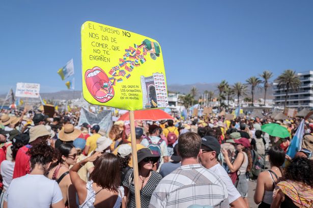 Los manifestantes marchan en Las Americas Beach durante una manifestación para protestar contra el turismo de masas, en Arona en la isla canaria española de Tenerife, el 20 de octubre de 2024. Miles de manifestantes que ondean las banderas salen a las calles de las islas canarias de España hoy para exigir cambios en el modelo de turismo de masas que, según dicen, está abrumando el arco del archipelago atlántico. Reuniendo bajo el eslogan "Las islas canarias tienen un límite"manifestantes que agitan banderas blancas, azules y amarillas de las Islas Canarias, marchados por turistas sentados en terrazas al aire libre en Playa de Las América antes de que se recuperen en la playa cantando "Esta playa es nuestra" Mientras los turistas sentados en las tumbonas debajo de las sombras Parasol miraban. (Foto de Desiree Martin / AFP) (Foto de Desiree Martin / AFP a través de Getty Images)