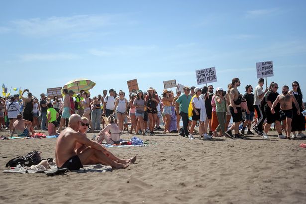 Los manifestantes marchan en Las Americas Beach durante una manifestación para protestar contra el turismo de masas, en Arona en la isla canaria española de Tenerife, el 20 de octubre de 2024. Miles de manifestantes que ondean las banderas salen a las calles de las islas canarias de España hoy para exigir cambios en el modelo de turismo de masas que, según dicen, está abrumando el arco del archipelago atlántico. Reuniendo bajo el eslogan "Las islas canarias tienen un límite"manifestantes que agitan banderas blancas, azules y amarillas de las Islas Canarias, marchados por turistas sentados en terrazas al aire libre en Playa de Las América antes de que se recuperen en la playa cantando "Esta playa es nuestra" Mientras los turistas sentados en las tumbonas debajo de las sombras Parasol miraban. (Foto de Desiree Martin / AFP) (Foto de Desiree Martin / AFP a través de Getty Images)