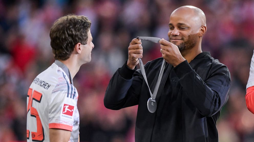 Kurioser Moment: Weil zwei Meister-Medaillen fehlen, überlasst Kompany Müller auf dem Podest seine