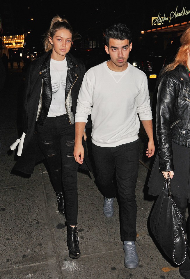 Gigi Hadid y Joe Jonas caminan por una calle de la ciudad por la noche.