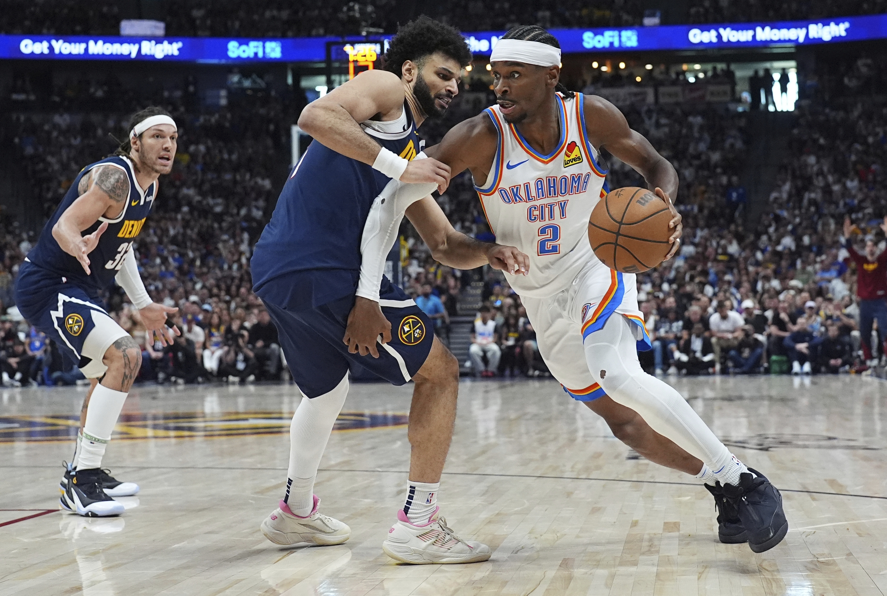 El guardia de Oklahoma City Thunder Shai Gilgeous-Alexander, a la derecha, pasa al guardia de los Nuggets de los Denver Jamal Murray, el centro y el delantero Aaron Gordon en la segunda mitad del Juego 4 en las semifinales de la Conferencia Oeste de los Playoffs de baloncesto de la NBA el domingo 11 de mayo de 2025, en Denver. (AP Photo/David Zalubowski)