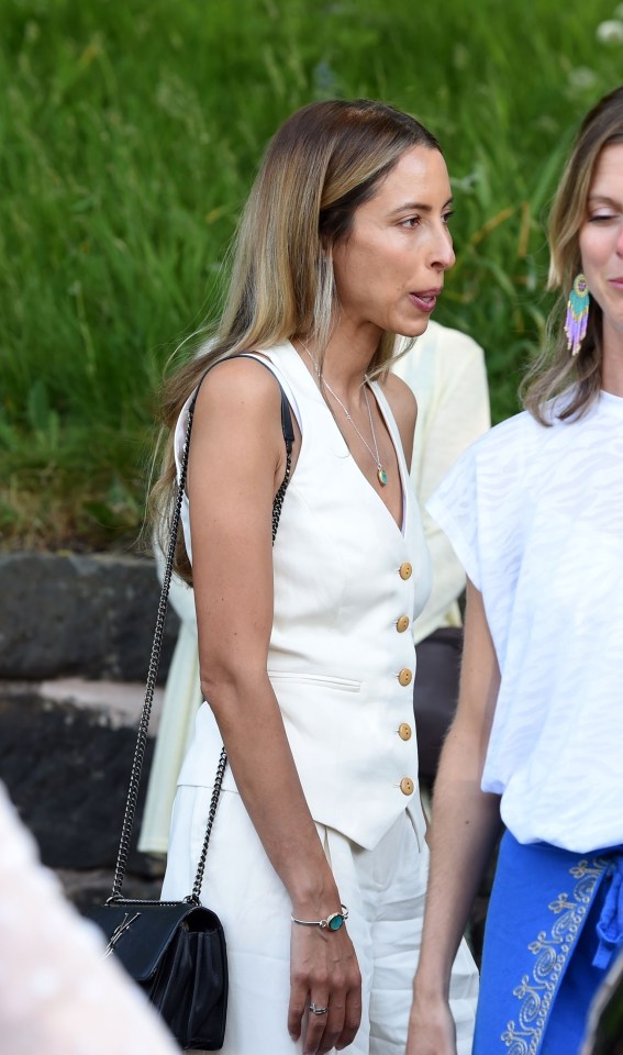 Mujer con chaleco blanco y pantalones en un funeral.