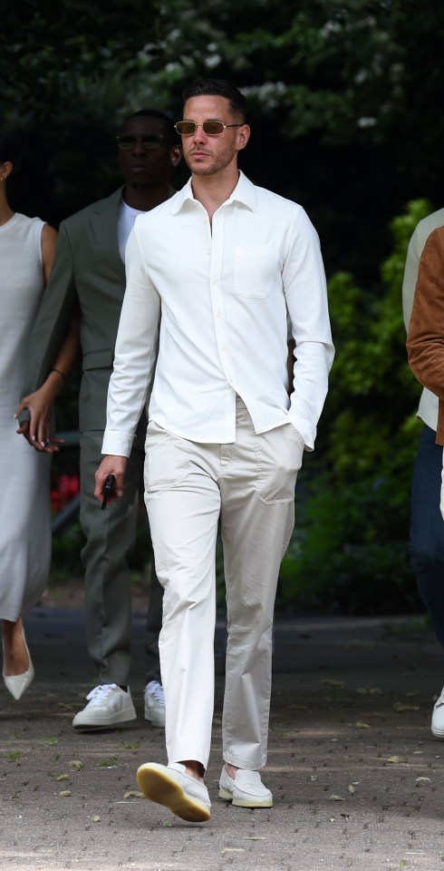 Un hombre con una camisa blanca y pantalones beige asiste a un funeral.