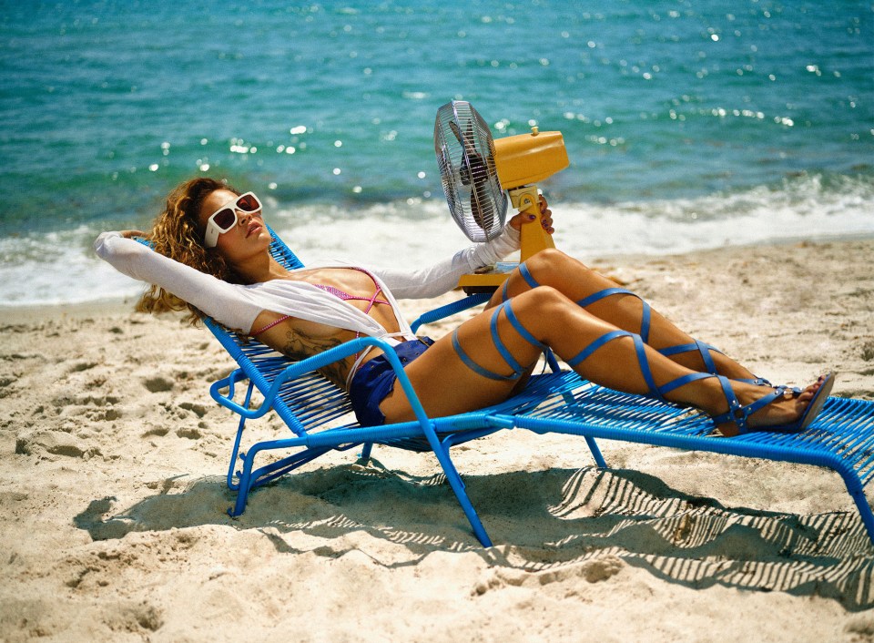 Mujer relajándose en una silla de playa azul con un pequeño ventilador.