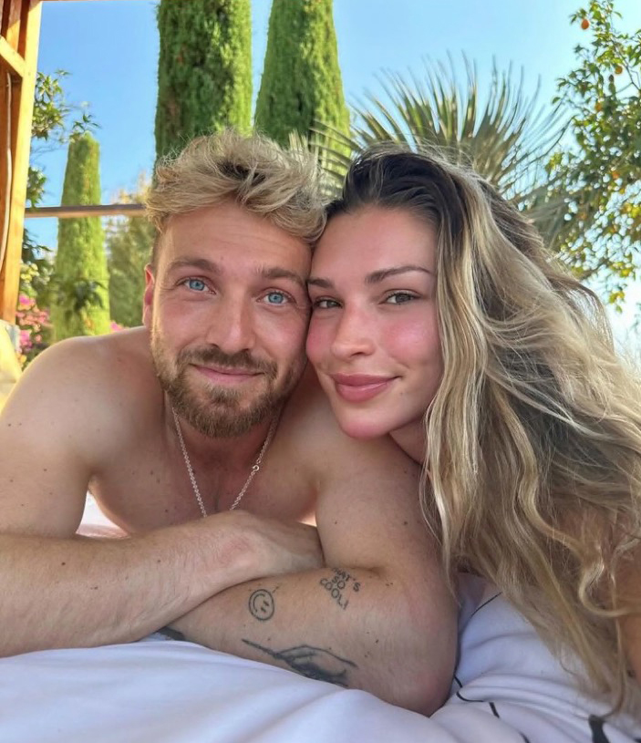 Sam Thompson y Zara McDermott acurrucan en una cama al aire libre.