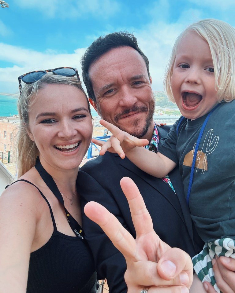 Selfie de una familia de tres, haciendo señales de paz.