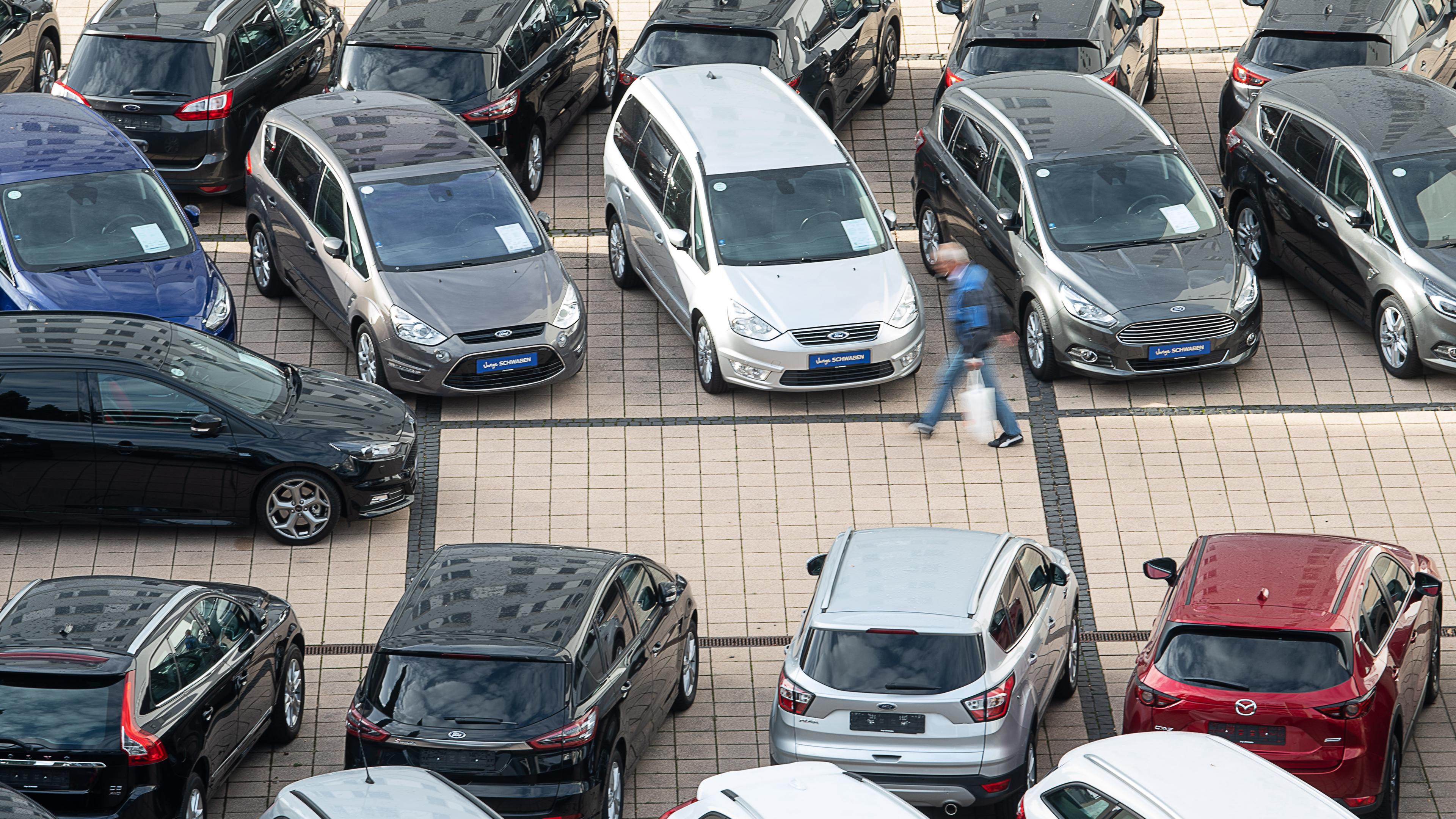Baden-Württemberg, Stuttgart: Un hombre pasa los autos usados en un concesionario de automóviles. Archivo