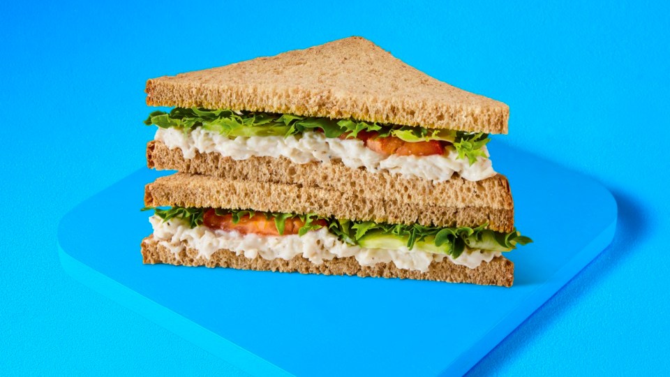 Sándwich de ensalada de pollo de dos pisos en pan integral.