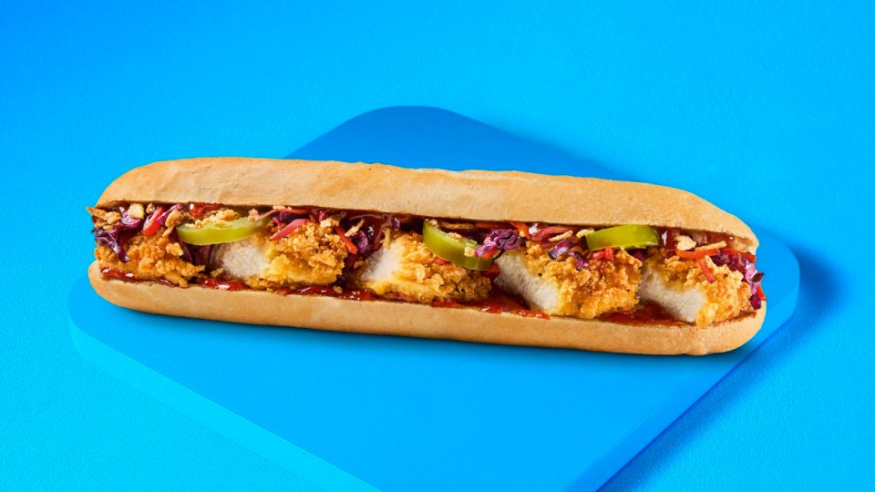 Sándwich de pollo crujiente en un rollo con repollo rojo y jalapeños.