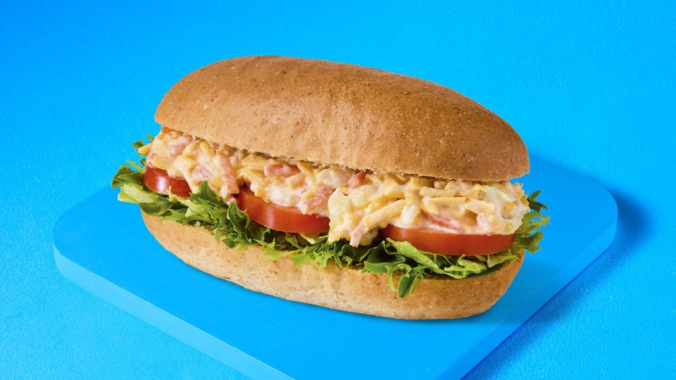 Sándwich con ensalada de huevo y tomate en un rollo de trigo integral.