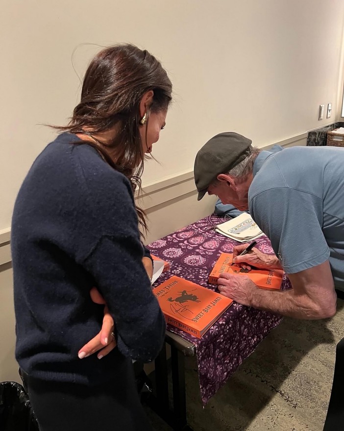 Meghan Markle viendo a James Taylor firmar un libro.