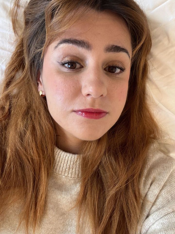 Primer plano selfie de una mujer con largo cabello castaño y maquillaje.