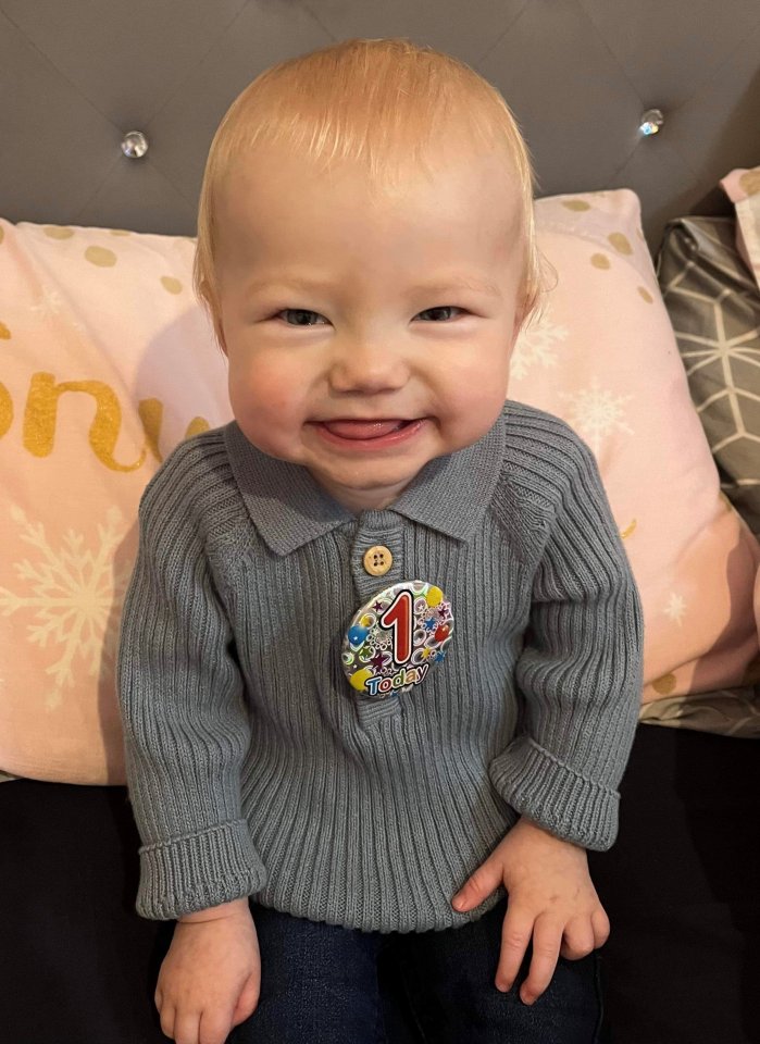 Foto de Archie Squire, un niño de un año, con un suéter gris con un "1 hoy" insignia.