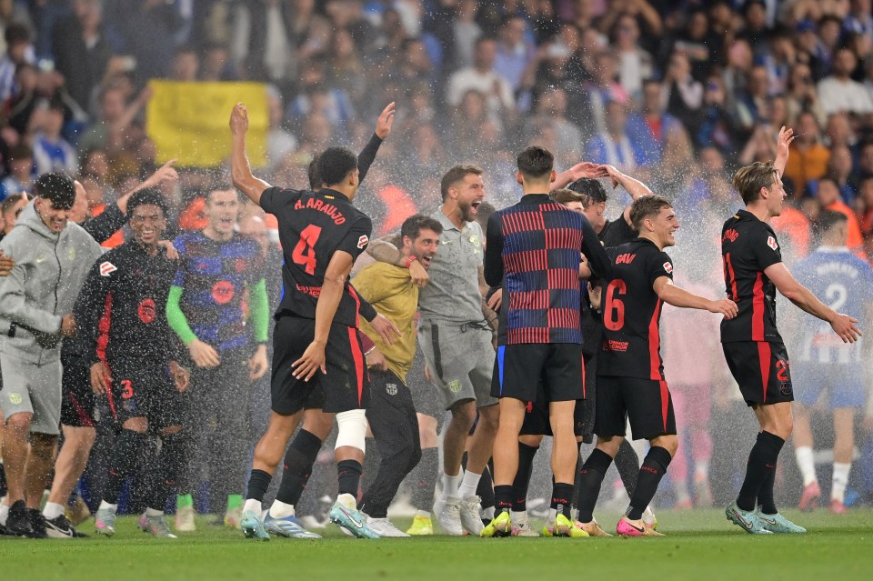Los jugadores de Barcelona celebran una victoria en el partido de fútbol bajo la lluvia.