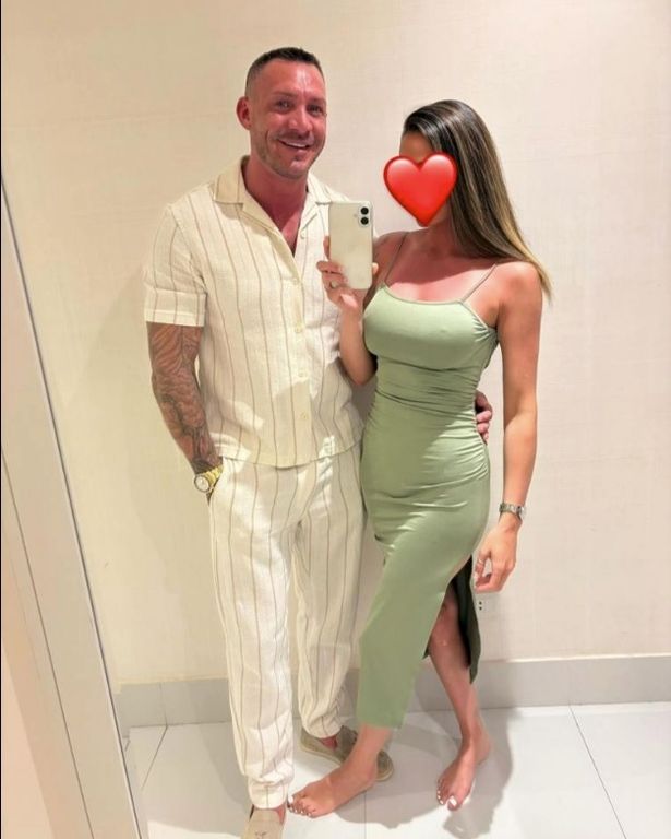 Kirk Norcross, en un conjunto de coordenadas blancas, y un compañero misterioso, con un vestido verde, con una selfie de vacaciones.