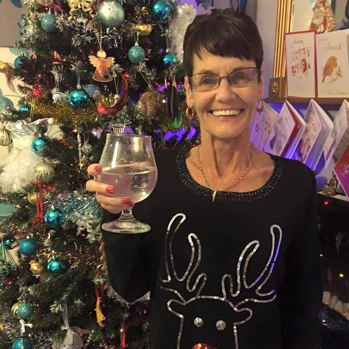 Catherine Flynn sosteniendo un vaso de agua frente a un árbol de Navidad.