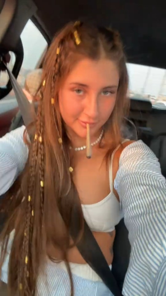 Selfie de una mujer joven fumando un porro en un automóvil.