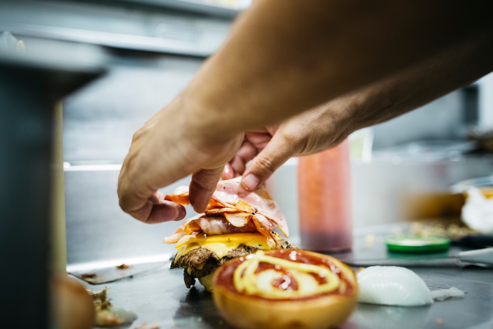 Chef preparando una hamburguesa con queso.