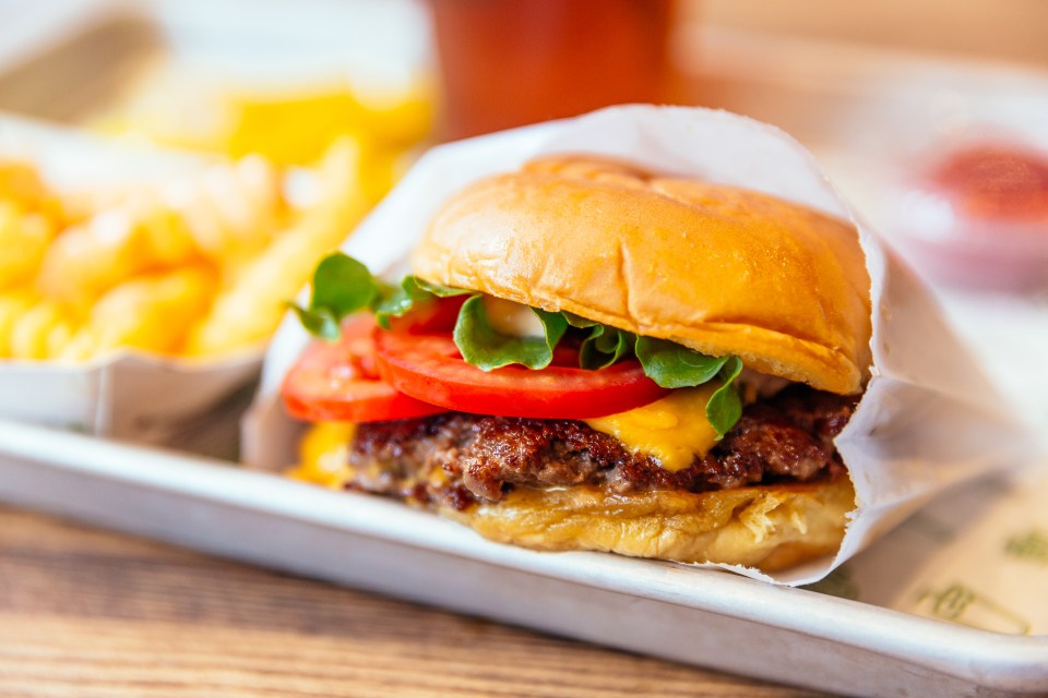 Hamburguesa con queso con lechuga y tomate, servida con papas fritas.
