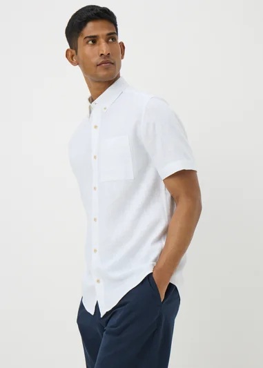 Hombre con una camisa blanca de manga corta y pantalones azul oscuro.