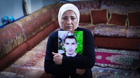 Rauda Hassan mira la cámara y agrupa una foto de su hijo secuestrado.