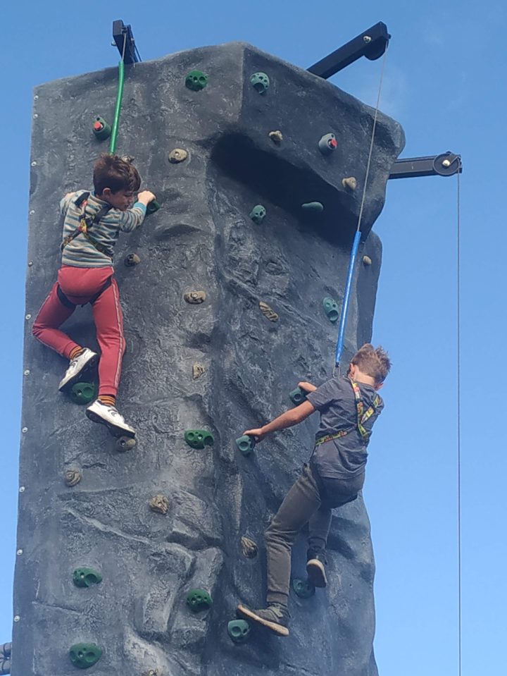 Dos niños trepando por una pared de roca.