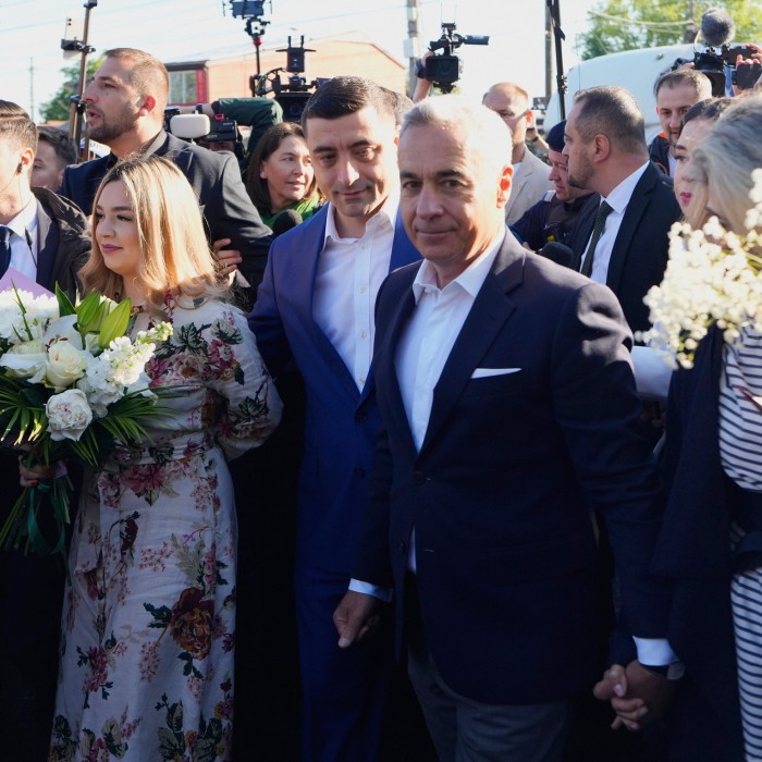 George Simion, centro, fuera de una estación de votación en Mogoșoaia con su esposa, Ilinca, y Călin Georgescu