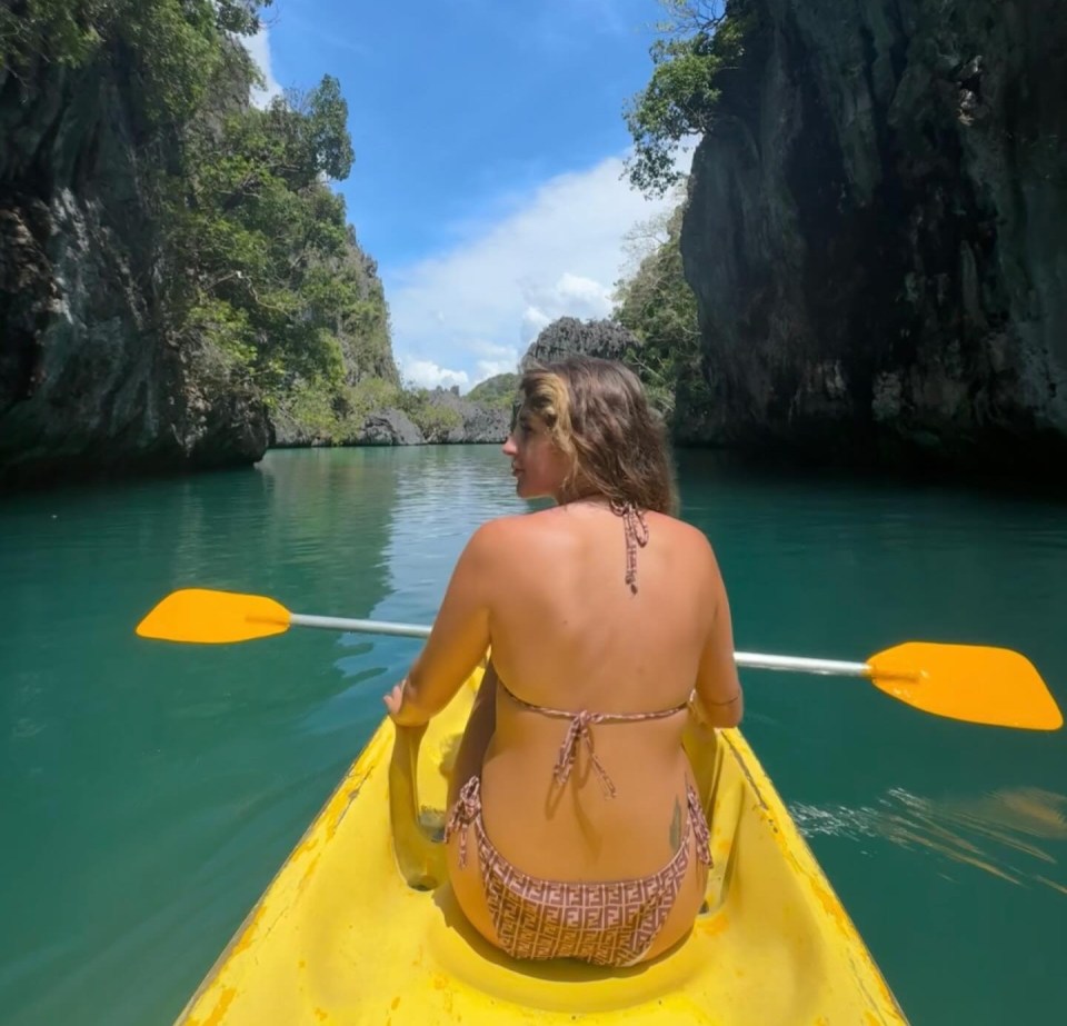 Mujer kayaking a través de una vía fluvial estrecha entre los acantilados de piedra caliza.
