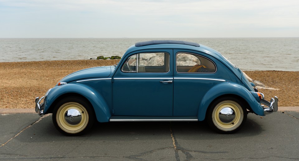 Blue Volkswagen Beetle estacionado por el océano.