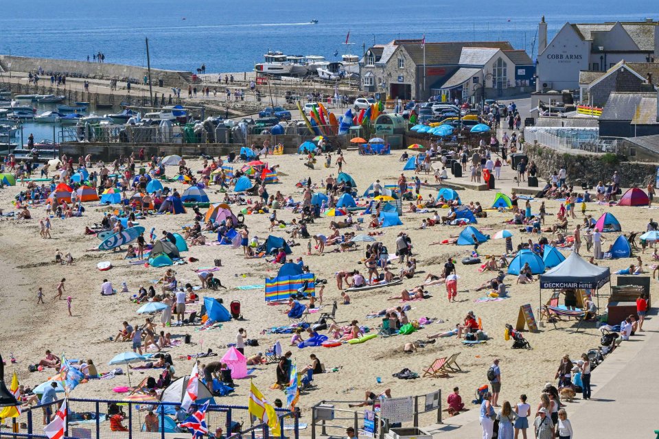 Playa llena de gente con bañistas y paraguas de playa.