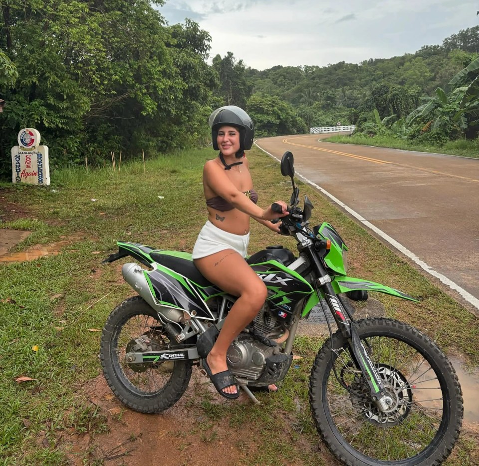 Mujer joven sentada en una motocicleta verde en Tailandia.