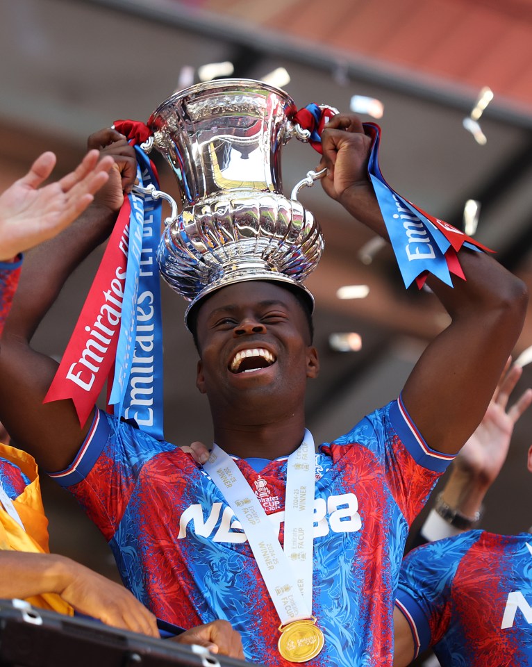 Marc Guehi de Crystal Palace sosteniendo el trofeo de la Copa FA sobre su cabeza.