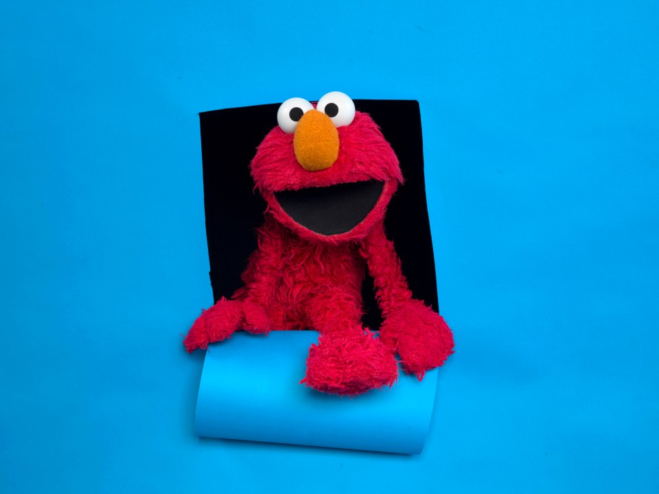 Elmo asomando a través de un agujero en un fondo azul.