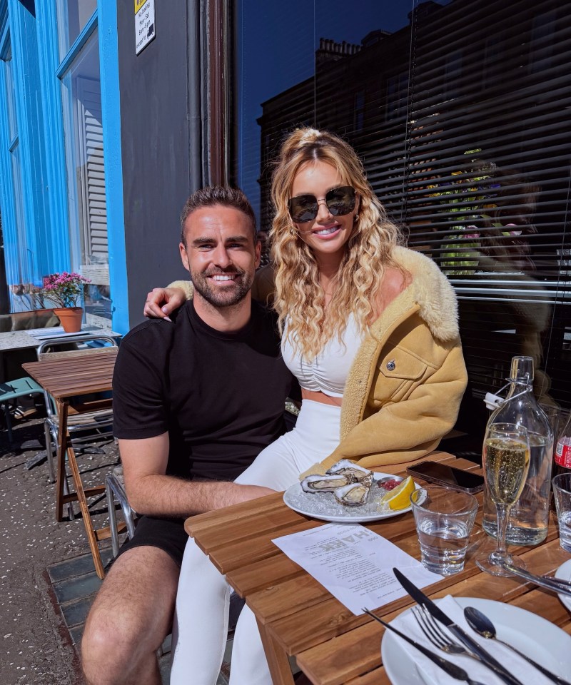 Pareja sentada en una mesa al aire libre disfrutando de ostras y champán.