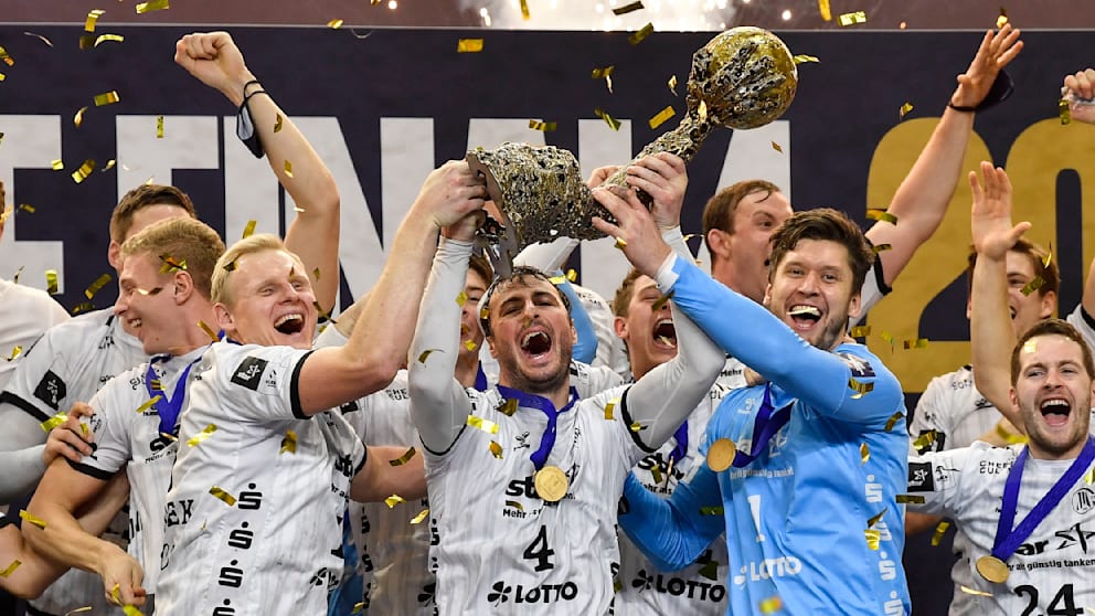Wiencek hält mit Domagoj Duvnjak und Torwart Niklas Landin den Champions-League-Pokal hoch. Im Finale 2020 schlug Kiel Barcelona 33:28