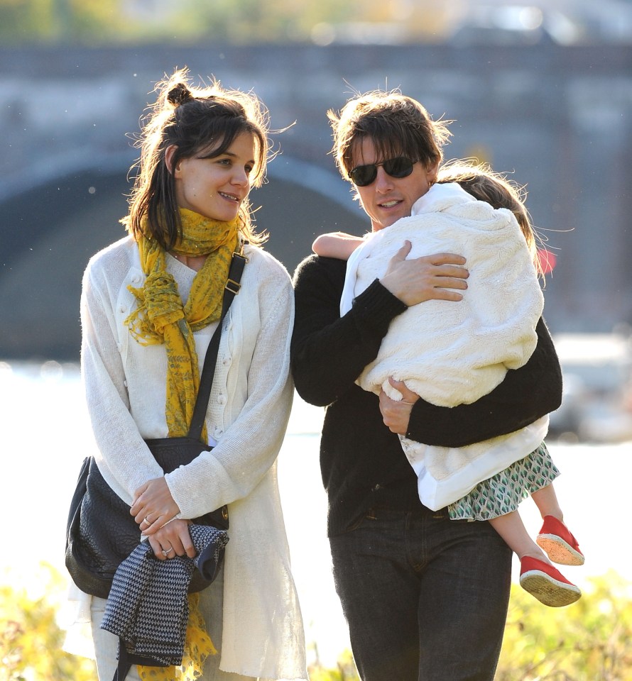 Tom Cruise, Katie Holmes y su hija Suri caminan juntos.
