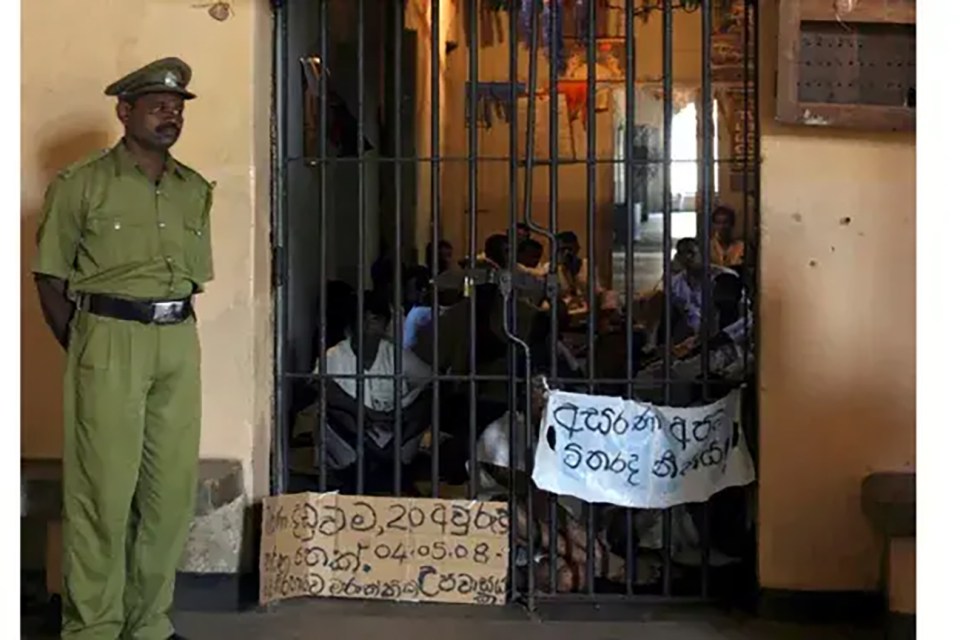Guard de pie afuera de una celda de prisión superpoblada en Sri Lanka.