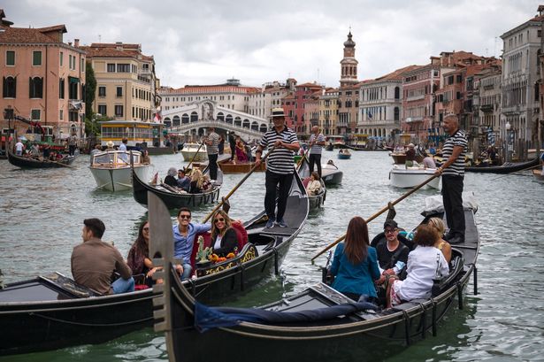 Los turistas disfrutan de un paseo en góndola en el Gran Canal junto al Puente Rialto en Venecia