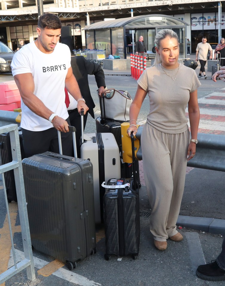 Molly Mae y Tommy Fury llegan a un aeropuerto con equipaje.