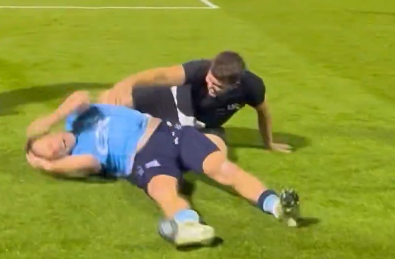 Captura de pantalla de dos jugadores de fútbol en el campo, uno en el suelo y el otro arrodillado sobre ellos.