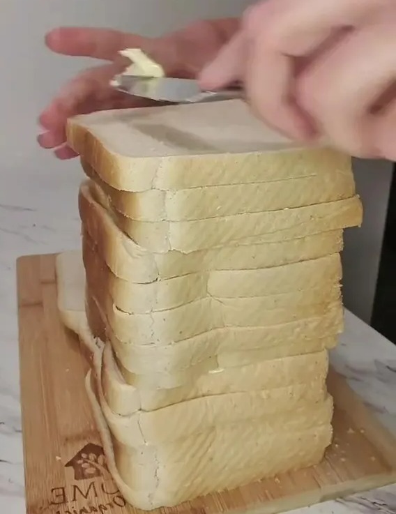 Mantequilla que se extiende en una gran pila de rebanadas de pan.