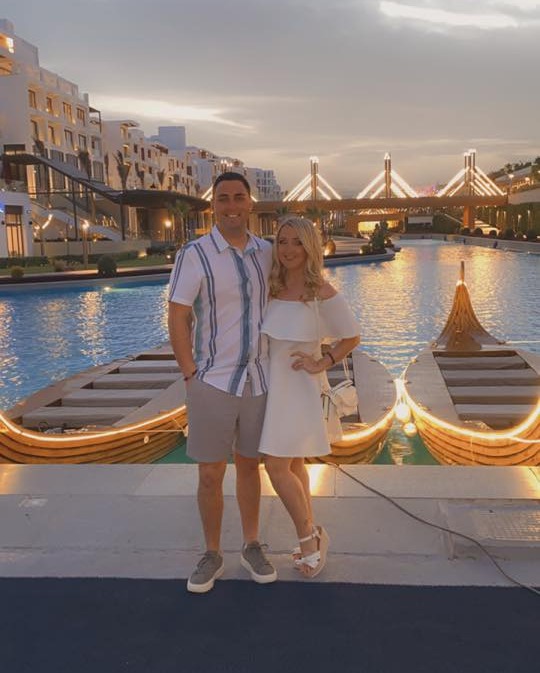 Pareja posando por botes iluminados en un resort.
