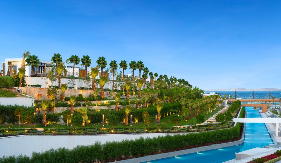 Rixos Radamis Resort Paisajismo con palmeras y una piscina.