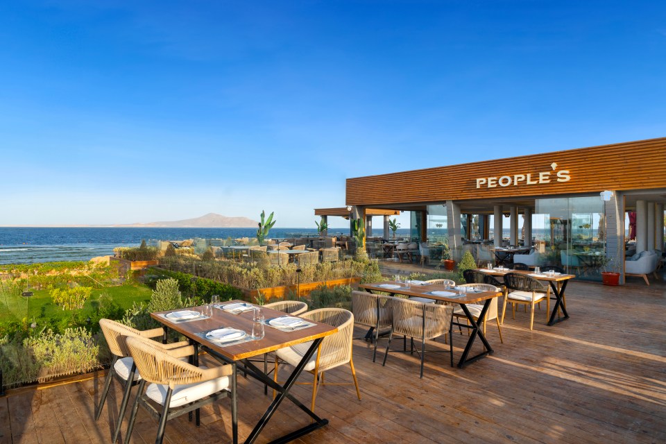 Restaurante al aire libre, gente, con vistas al mar.