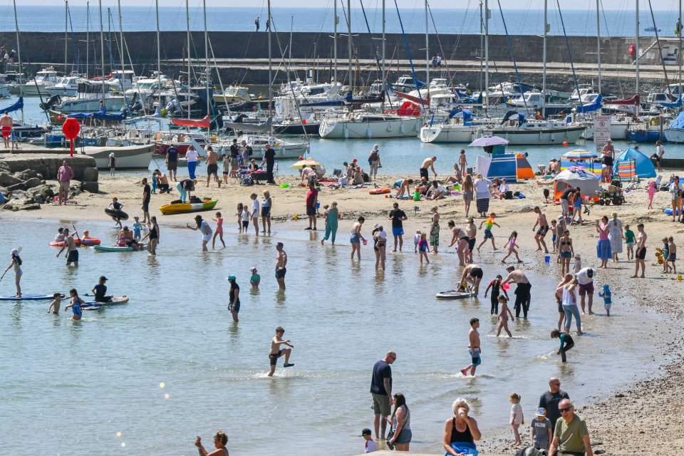 Bebathers disfrutando de un día caluroso en Lyme Regis Beach en Dorset, Reino Unido.
