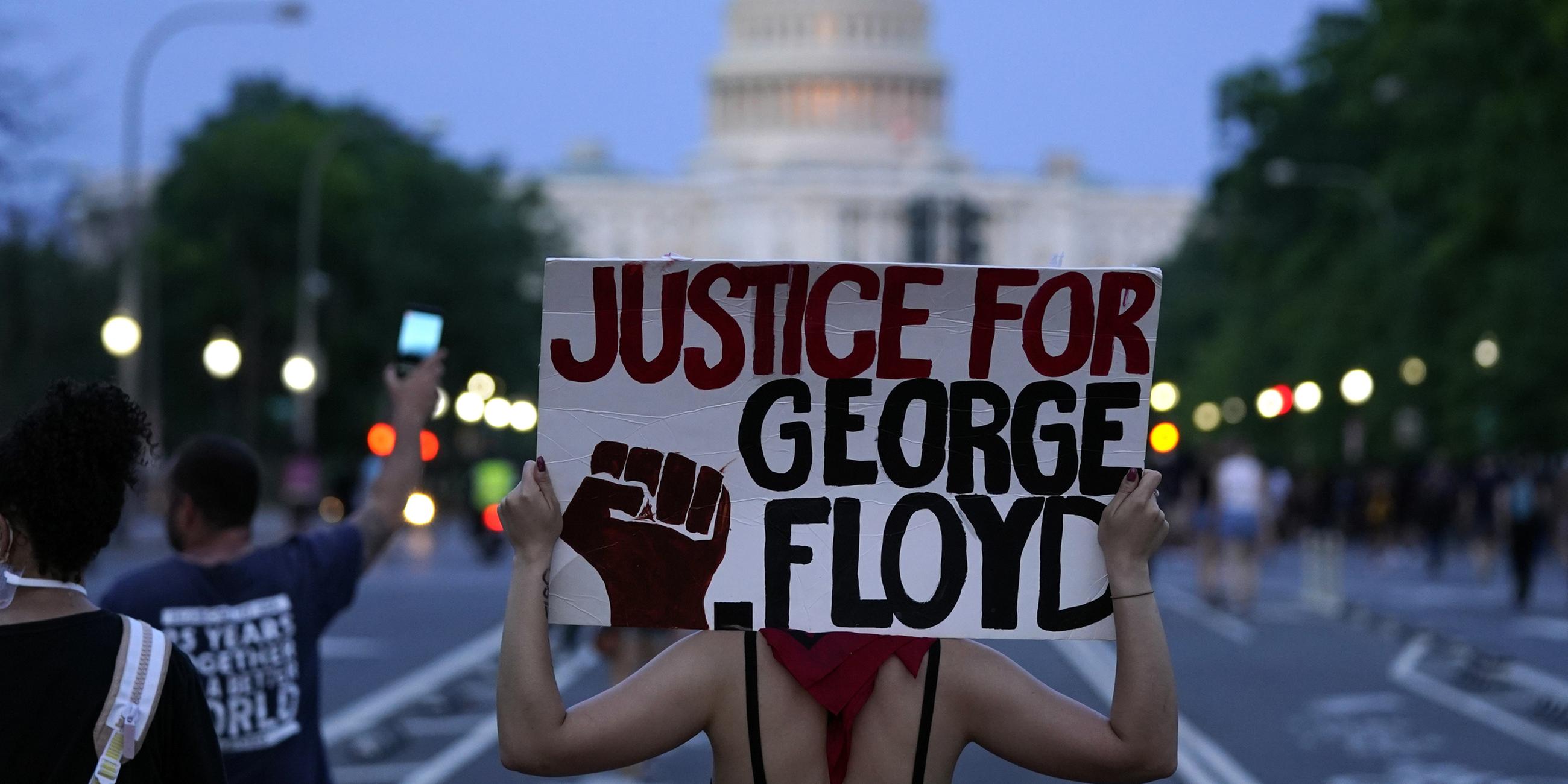 Mujer sostiene el póster con la inscripción "Justicia para George Floyd" En el curso de las protestas de BLM