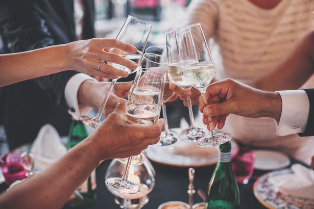 Gente de las manos tostadas con copas de champán en deliciosas fiesta al aire libre por la noche
