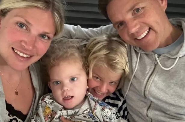 Emily (L) sosteniendo a Freddie con su esposo Louis (R) y otro hijo Henry